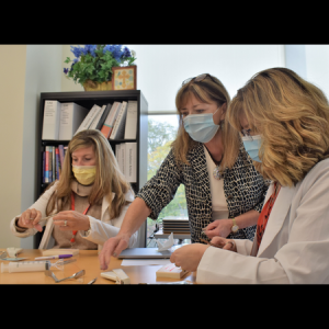 two FNP candidates practicing stitching with faculty at residency