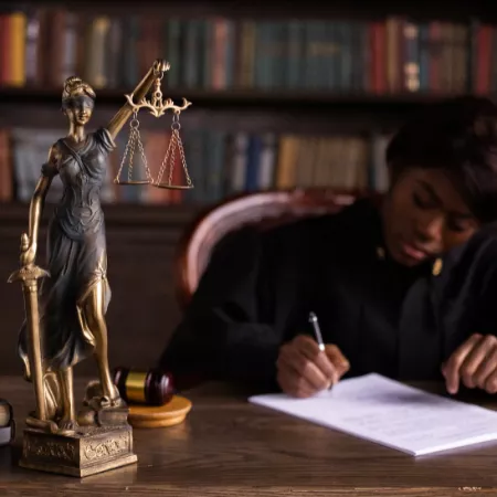 Statue of Justice on desk near woman writing