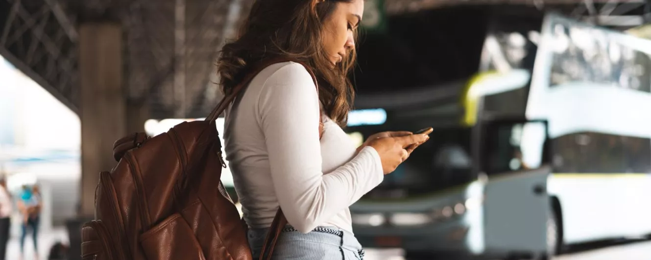 student on phone at a bus depot